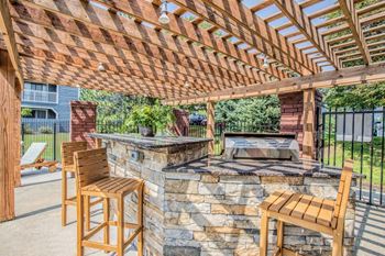 A wooden patio with a stone fireplace and two chairs.